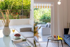 A modern outdoor seating area with a glass table, a wicker chair, and a sofa.