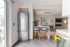 A modern kitchen with a built-in refrigerator, a dining area with two chairs, and a kitchen island. - Sunny Athenian Oasis Spacious Family Haven! (Kallithea)
