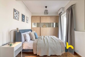 A bedroom with a bed, bedside table, and a wardrobe. - Sunny Athenian Oasis Spacious Family Haven! (Kallithea)