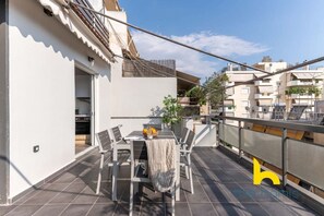 A rooftop terrace with a dining table, chairs, and a small plant. - Sunny Athenian Oasis Spacious Family Haven! (Kallithea)