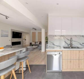 A modern kitchen with a marble countertop, wooden cabinets, and a built-in dishwasher. - Sunny Athenian Oasis Spacious Family Haven! (Kallithea)
