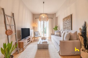 A modern living room with a flat-screen TV, a sofa, a coffee table, and a ladder against the wall. - Sun-Kissed Boho Haven with Whirlpool Bliss & Patio (Athina)