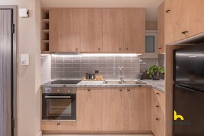 A modern kitchen with wooden cabinets, a stainless steel sink, and a built-in oven. - Sun-Kissed Boho Haven with Whirlpool Bliss & Patio (Athina)