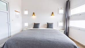 A neatly arranged bedroom with a large bed, two bedside tables, and a window with curtains. - Auberge Azul ifni (Sidi Ifni)