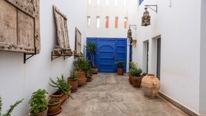 A narrow alleyway with a blue door, potted plants, and rustic decor. - Auberge Azul ifni (Sidi Ifni)