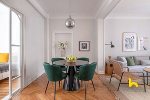 Un espace repas moderne avec une table ronde, des chaises recouvertes d’un tissu vert et un élément décoratif central.