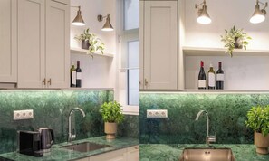 A kitchen with white cabinets, a green marble countertop, a coffee maker, a sink, and two potted plants. - Enchanted Haven Whimsical Elegance & Modern Bliss (Athina)
