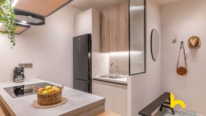 A modern kitchen with a built-in refrigerator, a sink, and a countertop with a basket of fruit. - Charming Boho Haven Luxurious Escape in Thisseio! (Athina)