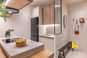 A modern kitchen with a built-in refrigerator, a sink, and a countertop with a basket of fruit. - Charming Boho Haven Luxurious Escape in Thisseio! (Athina)