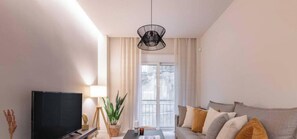 A modern living room with a flat-screen TV, a coffee table, a sofa, and a potted plant. - Charming Boho Haven Luxurious Escape in Thisseio! (Athina)