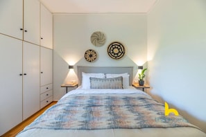 Ein Schlafzimmer mit Bett, Nachttischen, einem Kleiderschrank und Wanddekoration.