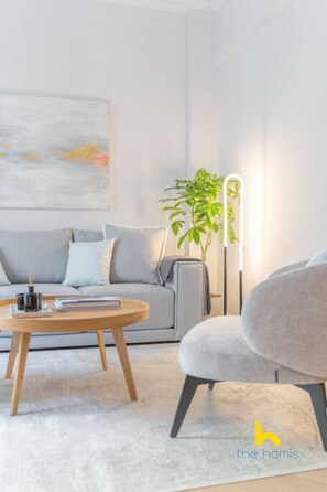 A modern living room with a grey sofa, a round wooden coffee table, a grey armchair, and a tall floor lamp. - Spacious 3BR Retreat w/ 2 Baths + Fast Wi-Fi (Vironas)