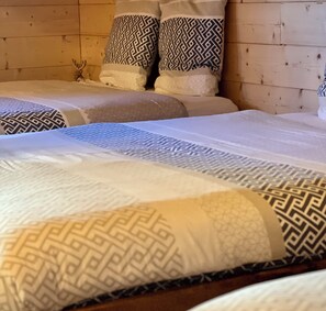 Una cama con ropa de cama y almohadas estampadas, cabecera de madera y pared de madera.