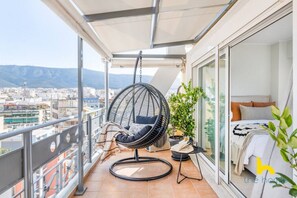 Ein Balkon mit einer Hängematte, einem kleinen Tisch mit einer Pflanze und einem Bett mit Kissen.