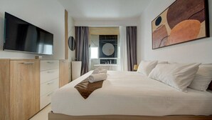 Ein modernes Hotelzimmer mit einem großen Bett, einem Flachbildfernseher, einem Kleiderschrank und einem Gemälde an der Wand.