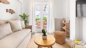 A modern living room with a sofa, a round coffee table, and a potted plant. - Rooftop Hideaway w/ Large Private Patio near Metro (Athina)