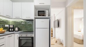 A modern kitchen with white cabinets, a built-in oven, a microwave, and a coffee maker. - Rooftop Hideaway w/ Large Private Patio near Metro (Athina)