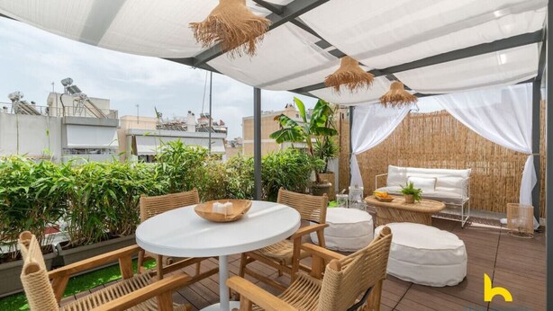 An outdoor patio with a round table, wicker chairs, a white sofa, and a bamboo backdrop. - Rooftop Hideaway w/ Large Private Patio near Metro (Athina)
