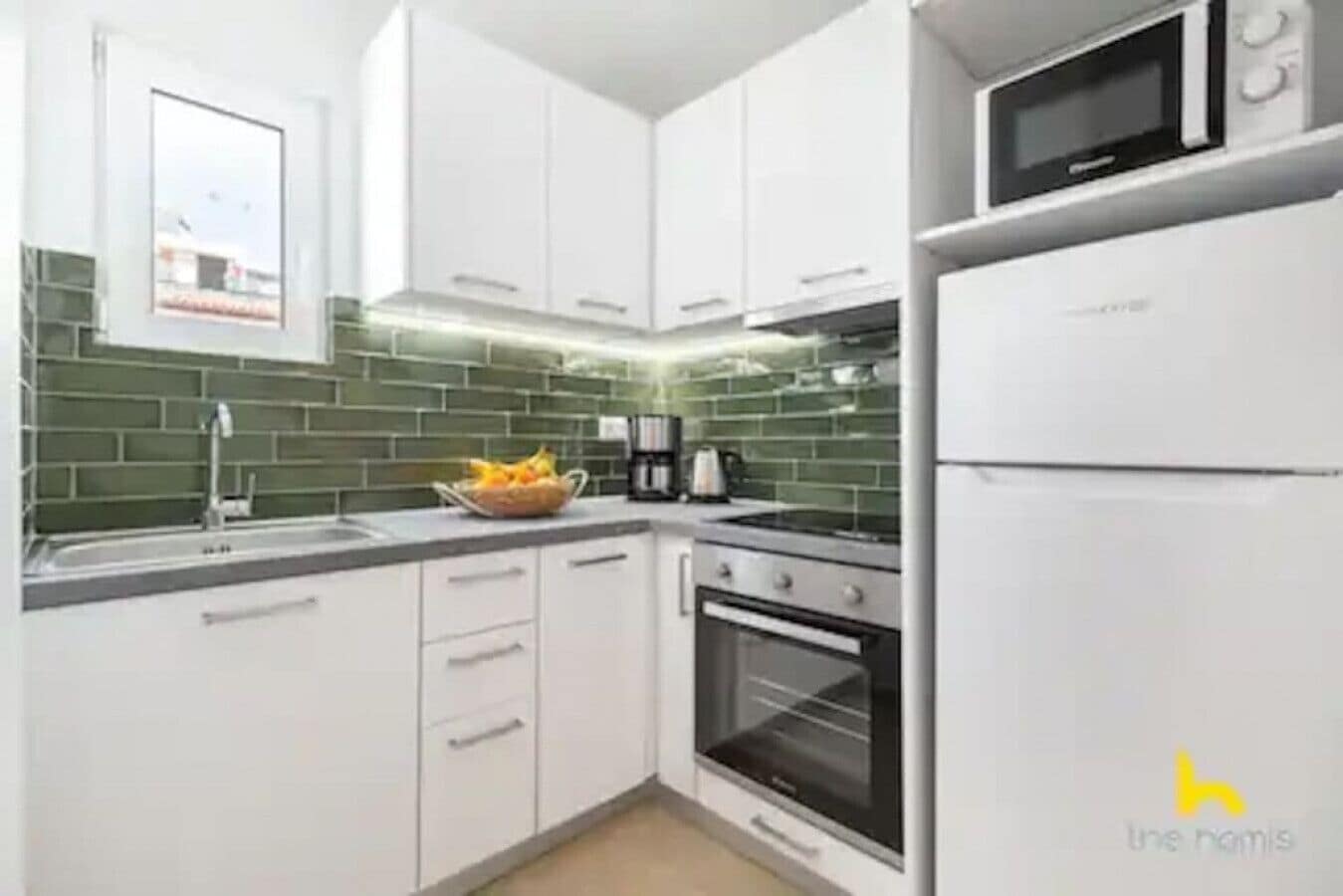 Eine moderne Küche mit weißen Schränken, einer Mikrowelle und einem Kühlschrank.