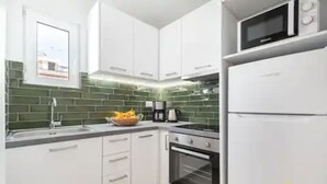 A modern kitchen with white cabinets, a microwave, and a refrigerator. - Rooftop Hideaway w/ Large Private Patio near Metro (Athina)