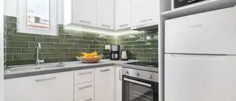 A modern kitchen with white cabinets, a microwave, and a refrigerator.