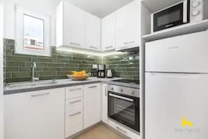 A modern kitchen with white cabinets, a microwave, and a refrigerator. - Rooftop Hideaway w/ Large Private Patio near Metro (Athina)