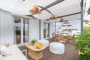 A modern outdoor patio with wicker furniture, a round table with fruit, and a white canopy. - Rooftop Hideaway w/ Large Private Patio near Metro (Athina)