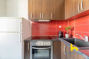 A kitchen with wooden cabinets, a built-in oven, a sink, and a countertop. - Light-Filled, Central Athens Escape near Acropolis (Athina)