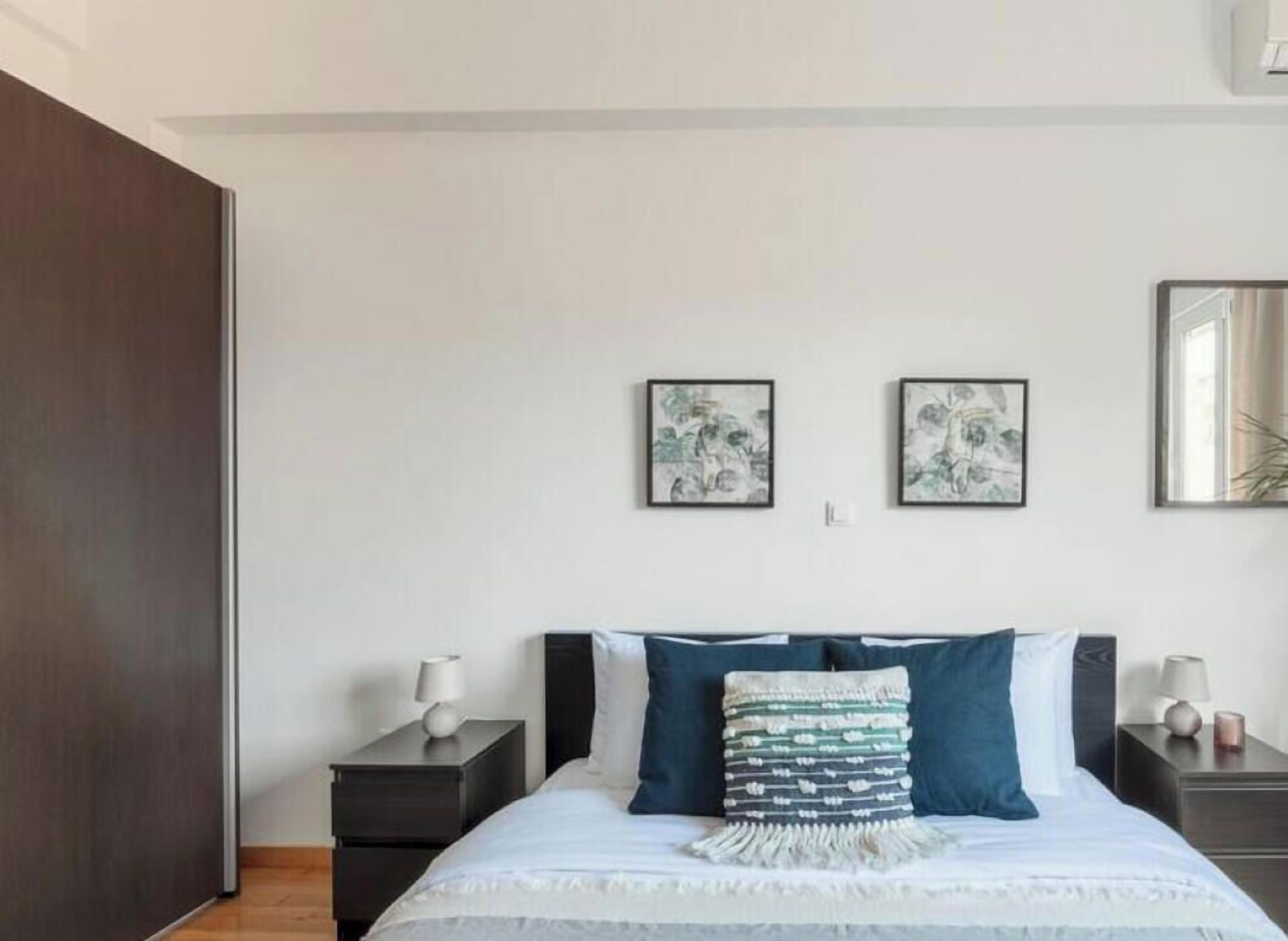 Una camera da letto con un letto, due comodini e due quadri appesi al muro.