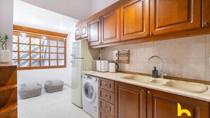 Une cuisine de taille réduite, avec des meubles de rangement en bois, un lave-linge et un évier.