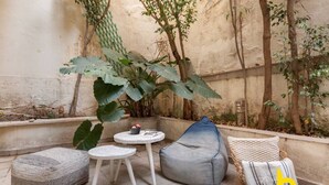 Un petit espace patio avec une table ronde, un fauteuil en forme de poire et un banc rembourré.