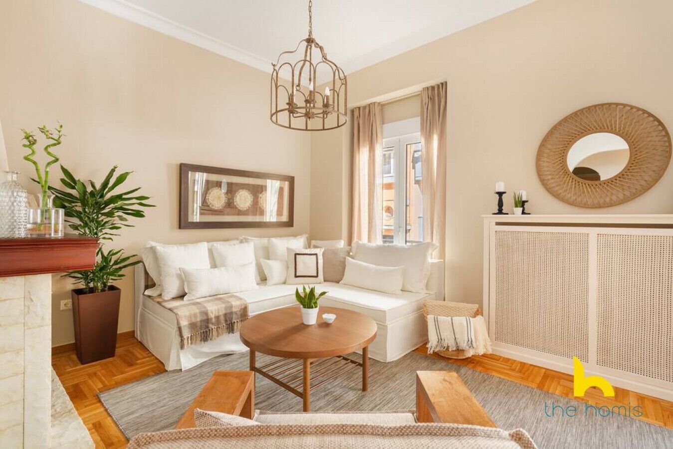 Ein Wohnzimmer mit einem weißen Sofa, einem Holztisch, einem Blumentopf, einem gerahmten Kunstwerk und einem großen Spiegel an der Wand.