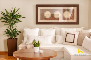 A living room with a white sofa, a round wooden coffee table, and a potted plant. - Grand Family APT with Courtyard near Acropolis! (Athina)