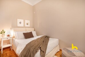 A bedroom with a bed, bedside table, and wall art. - Grand Family APT with Courtyard near Acropolis! (Athina)