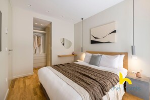 A modern bedroom with a large bed, a bedside table, a mirror, and a wall-mounted abstract art piece. - Urban APT with Stunning Acropolis View & Roofdeck (Athina)