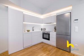 Une cuisine moderne avec des armoires blanches, un réfrigérateur en acier inoxydable et un four encastré.