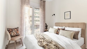 Una camera da letto con un letto, una sedia e un balcone con tende.
