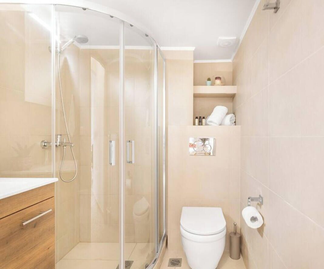 A modern bathroom with a glass-enclosed shower, a white toilet, and a wooden vanity.