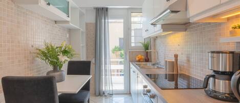 Una cocina moderna con comedor, que incluye una isla, horno empotrado y cafetera.