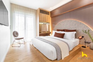 Quarto moderno com uma cama grande, um espaço para sentar e uma penteadeira com espelho.