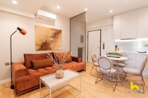 Uma sala de estar moderna com um sofá marrom, uma mesa de centro e uma área de jantar com uma mesa redonda e cadeiras.