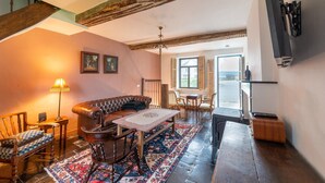 A cozy living room with a leather sofa, wooden coffee table, and patterned rug. - Charming holiday home with garden (Dinant)