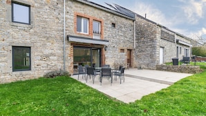 A stone building with a patio area featuring outdoor seating. - Charming holiday home with garden (Dinant)