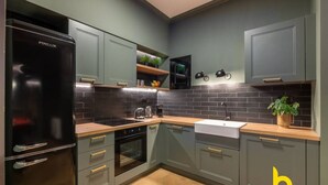 A modern kitchen with grey cabinets, a black refrigerator, a wooden countertop, and a sink. - Unique Urban Cave w/ Pool Table Near Acropolis! (Athina)