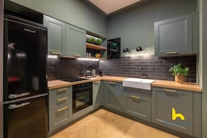 A modern kitchen with grey cabinets, a black refrigerator, a wooden countertop, and a sink. - Unique Urban Cave w/ Pool Table Near Acropolis! (Athina)