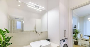Une salle de bain moderne avec un lavabo blanc, un miroir, un porte-serviettes et un lave-linge.