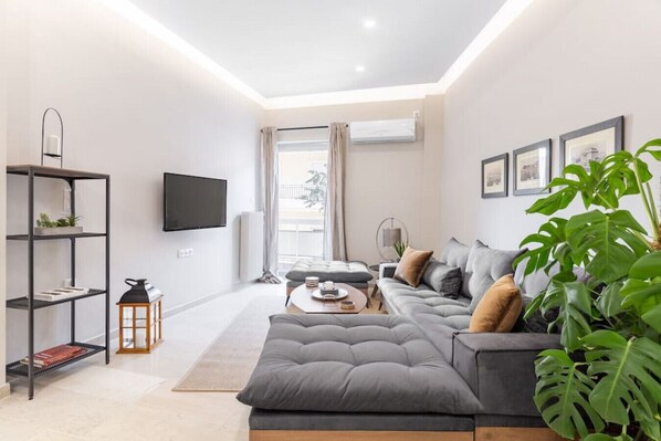 A modern living room with a grey sofa, a coffee table, and a bookshelf.
