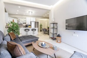 A modern living room with a grey sofa, a coffee table, and a TV mounted on the wall.
