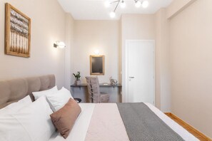 A bedroom with a bed, a desk, and a chair.