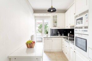 A modern kitchen with white cabinetry, a black countertop, and a hanging light fixture. - Comfortable & Quiet Family APT Near Acropolis (Athina)